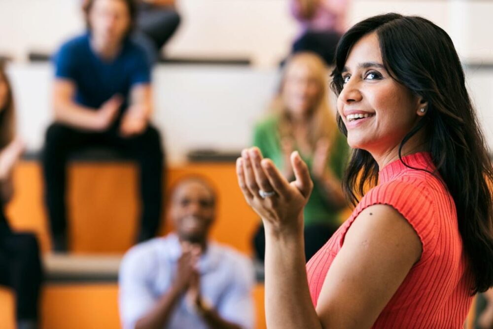 /woman-with-dark-hair-presenting-to-informal-conference-looking-back-over-her-shoulder.jpg